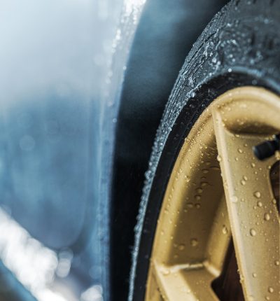 Weather Elements and the Car Wheels. Water on Elegant Golden Alloy Wheels. Transportation and Automotive Industry Theme.