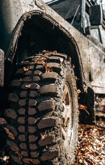 Wheel of offroad car in a muddy roadn forest close up