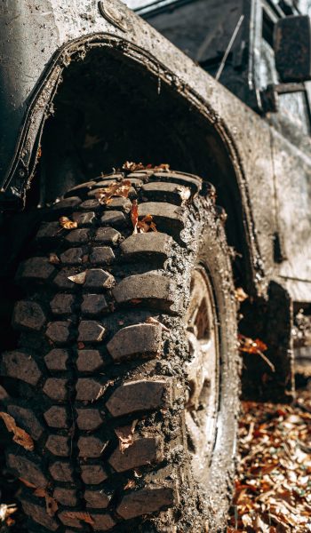 Wheel of offroad car in a muddy roadn forest close up